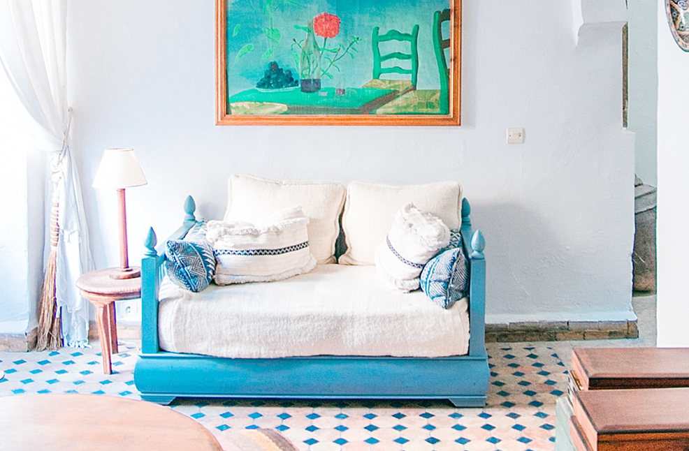 Blue couch with white pillows in a white room.