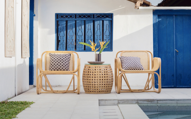 Two patio wicker chairs in front of a blue window.