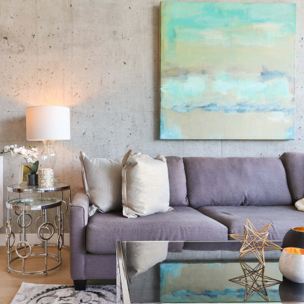 a purple couch in the living room with a coffee table in front and a side table with a lamp on it